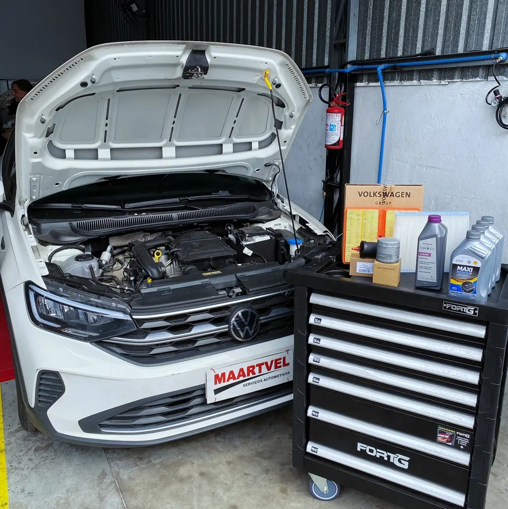 Volkswagen com o capô aberto e kit de óleo e filtros originais ao lado, durante a troca de óleo na Maartvel